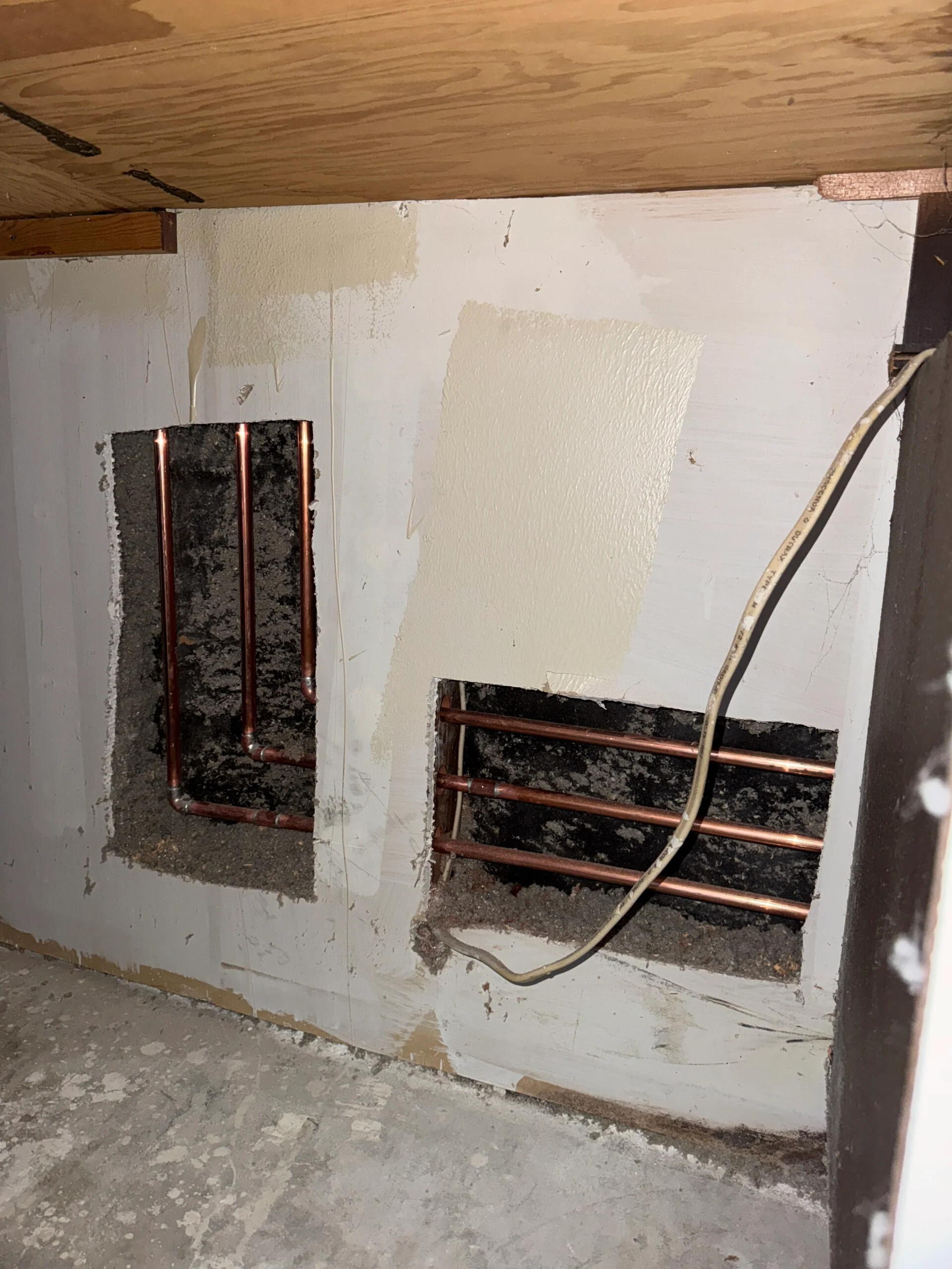 Plumbing access openings behind laundry utility wall